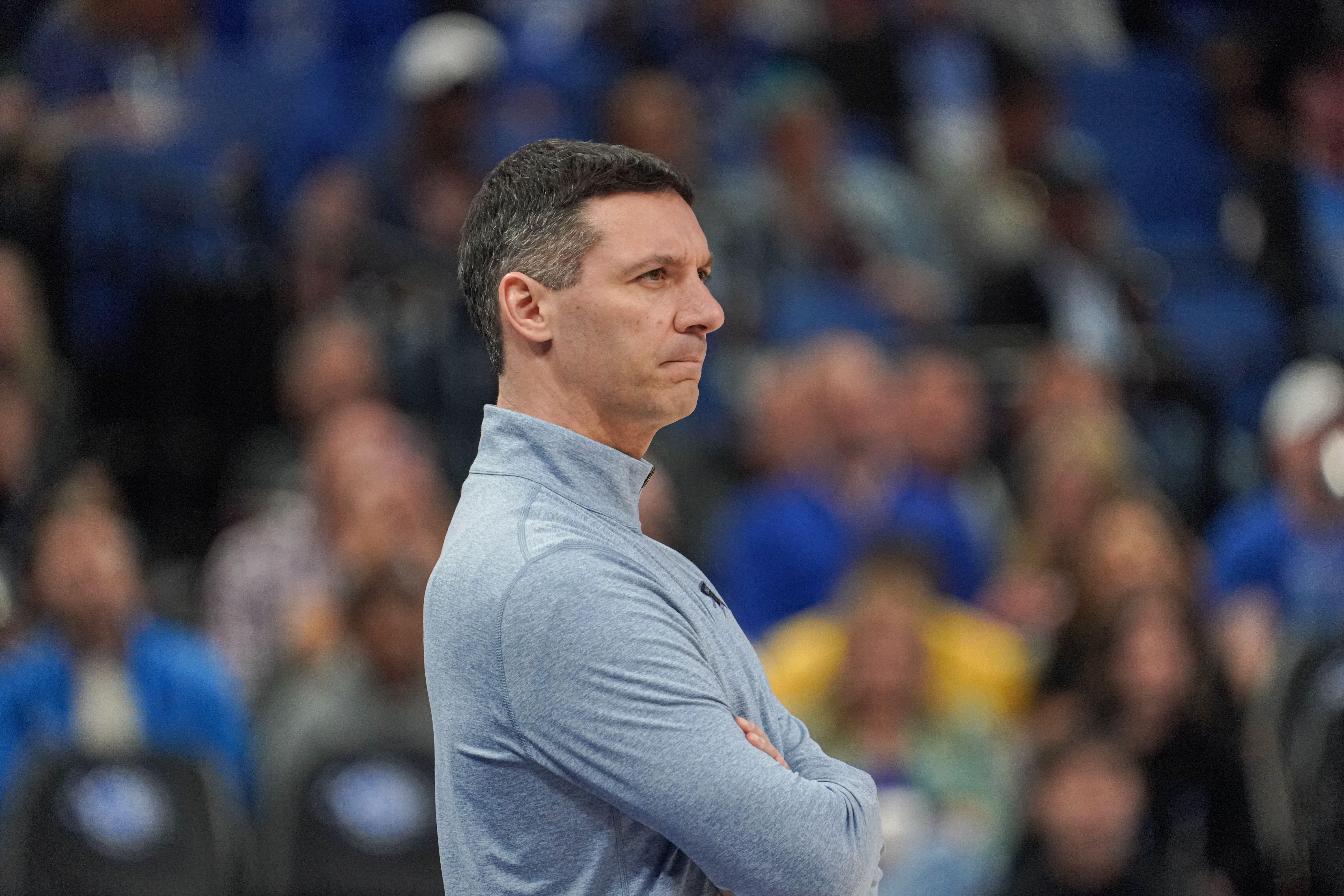 Basketball coach with arms crossed in a blue pullover