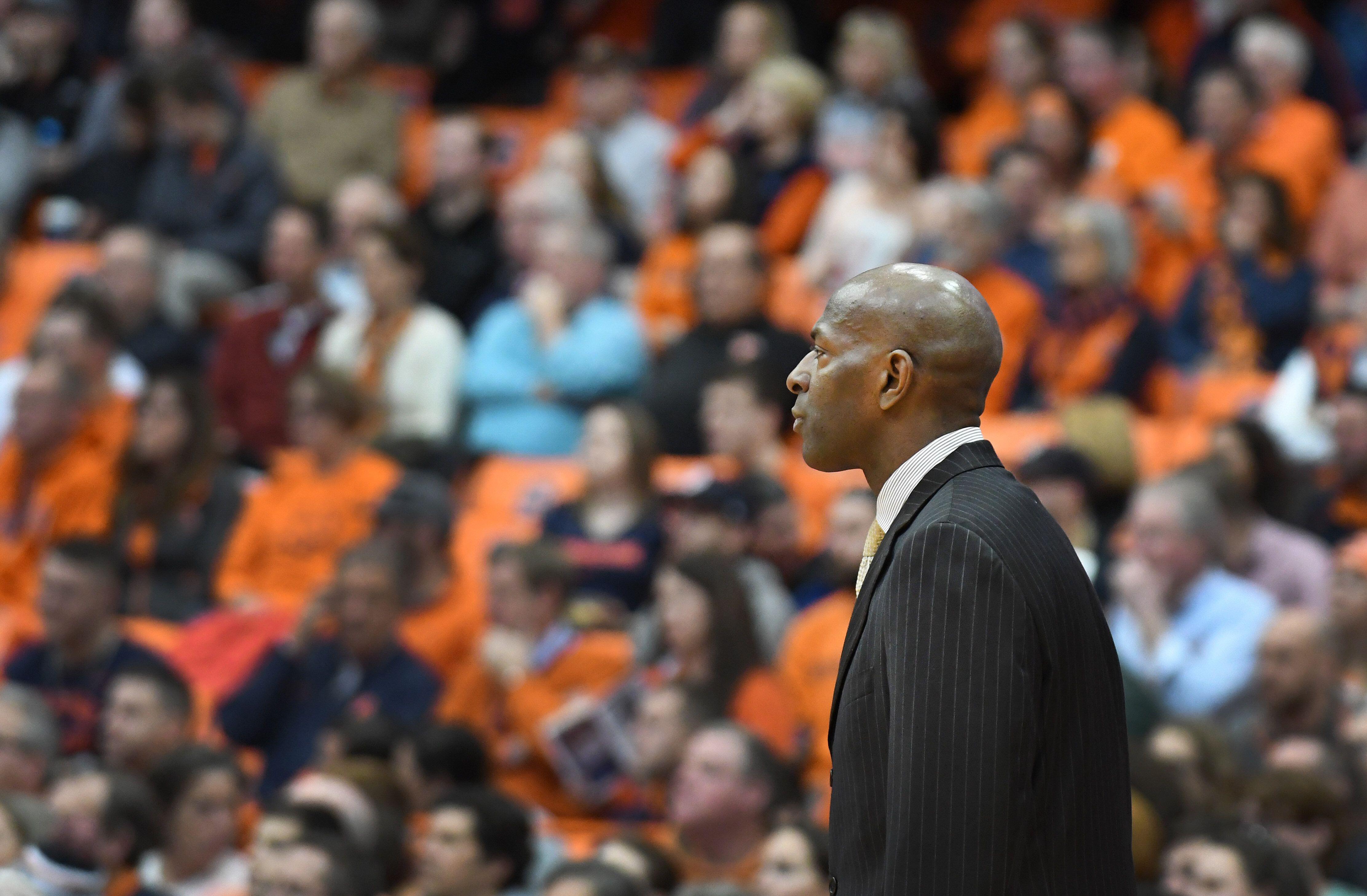 Basketball coach in a pinstriped suit observing the court