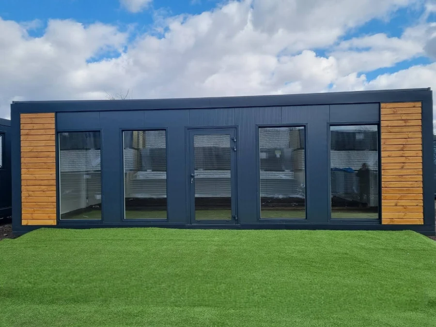 Wohncontainer mit Glasfront und Holzakzenten auf Rasen