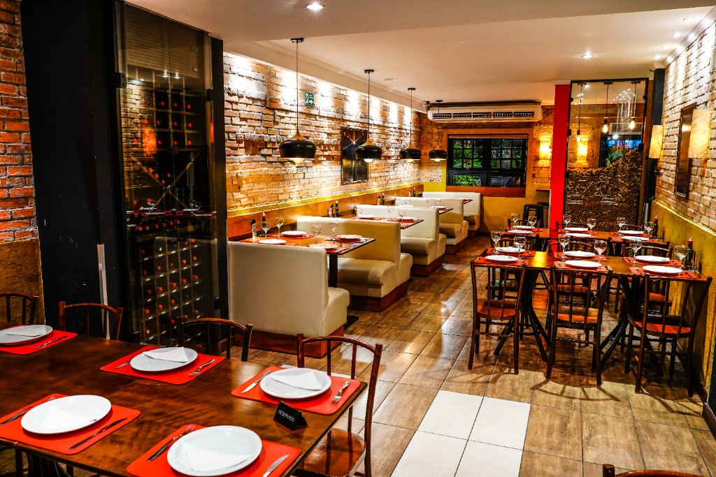 Mesa posta com taças de vinho no salão da Pizzaria Qualitá