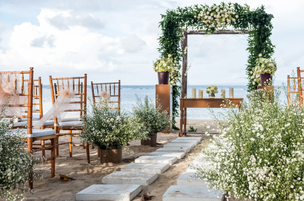 Beach wedding ceremony setup with a floral arch and guest chairs overlooking the ocean