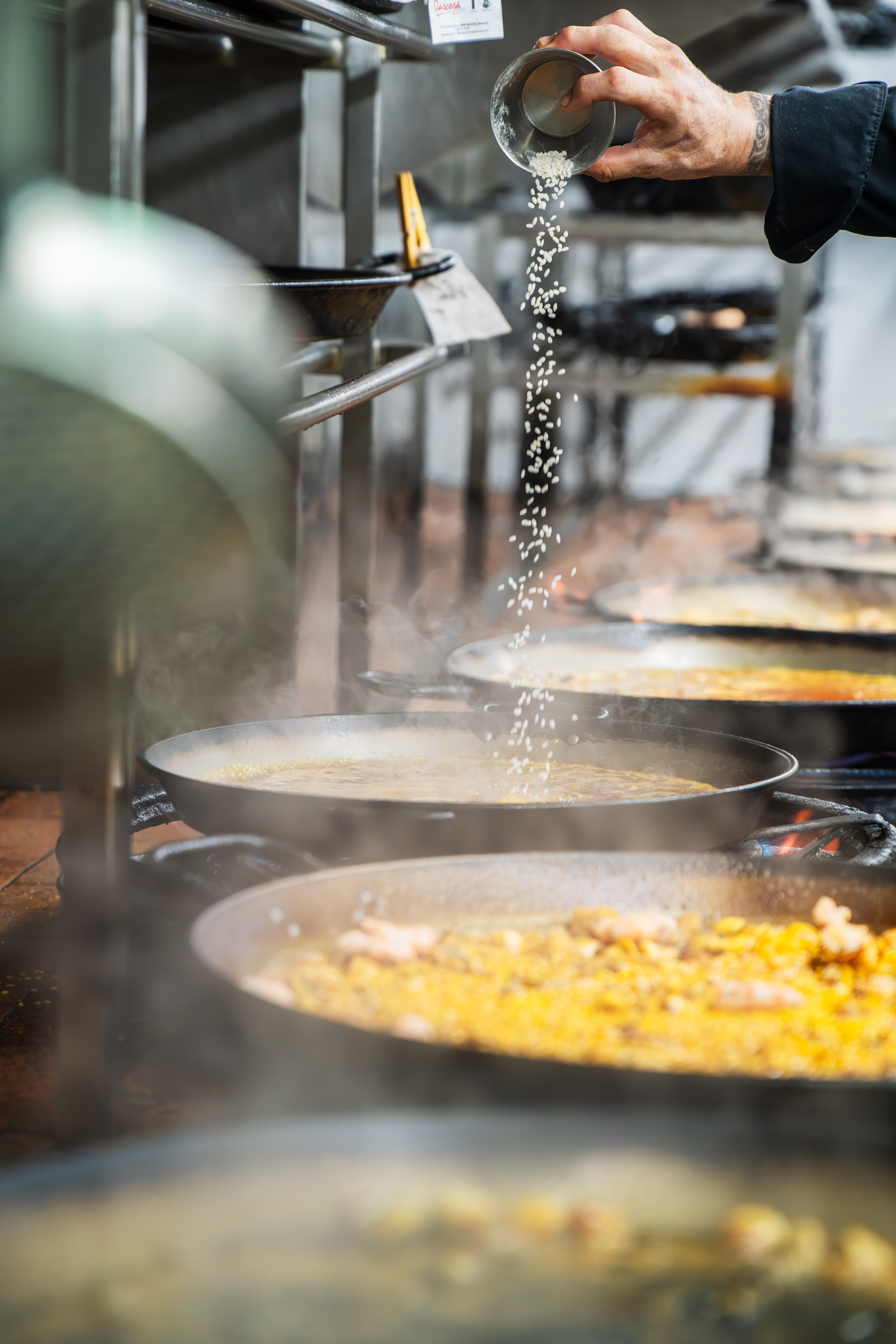 Arroz cayendo en la paellera durante la receta tradicional