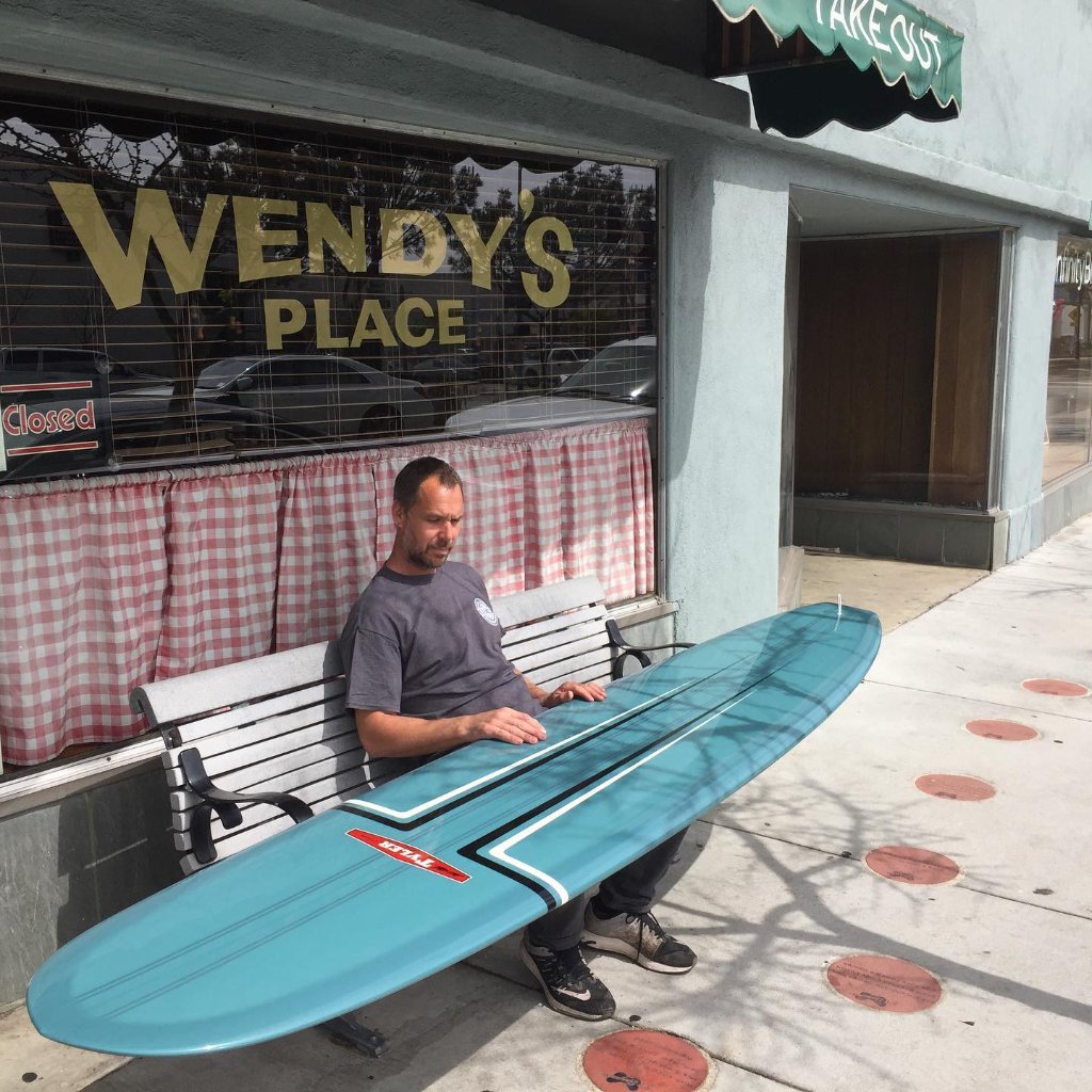 Tyler inspecte un longboard bleu chez Wendy's Place