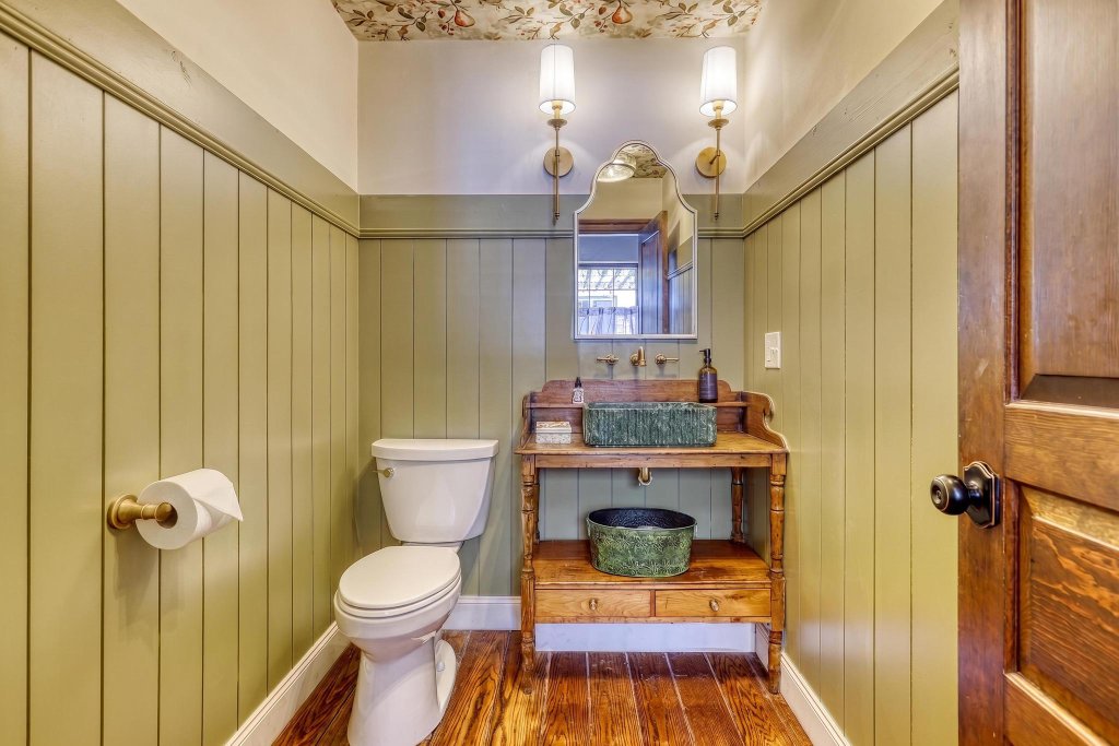 Rustic bathroom with vintage vanity, brass fixtures, and botanical wallpaper