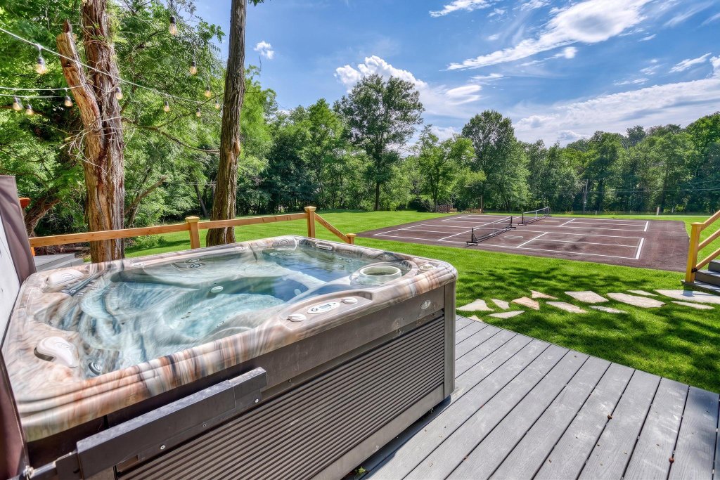 Hot tub on the deck overlooking the lawn and sports court