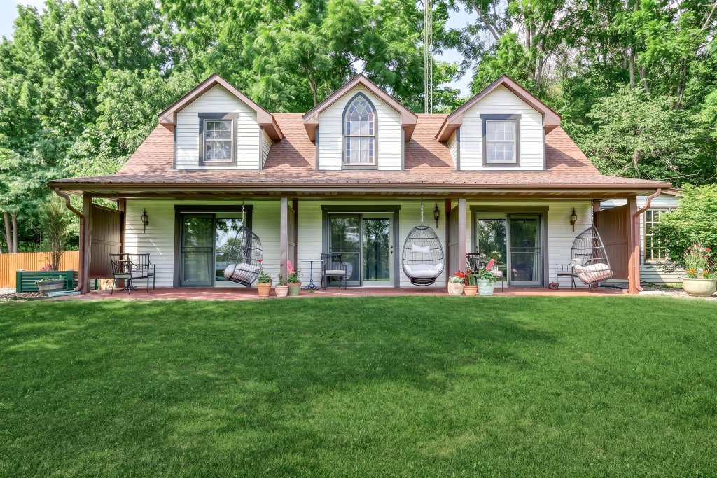 Carriage House back facade with covered patio and hanging egg chairs overlooking the lawn