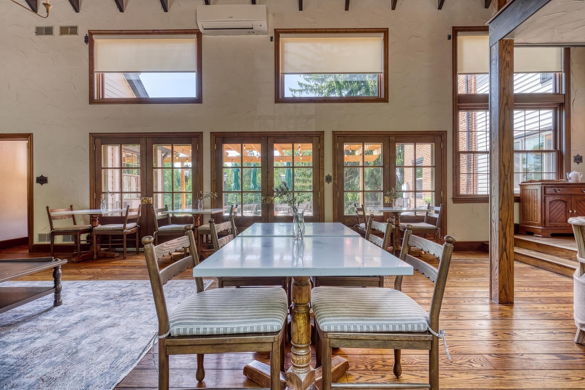 Great Room dining table with marble top and carved wood chairs beside French doors to the patio