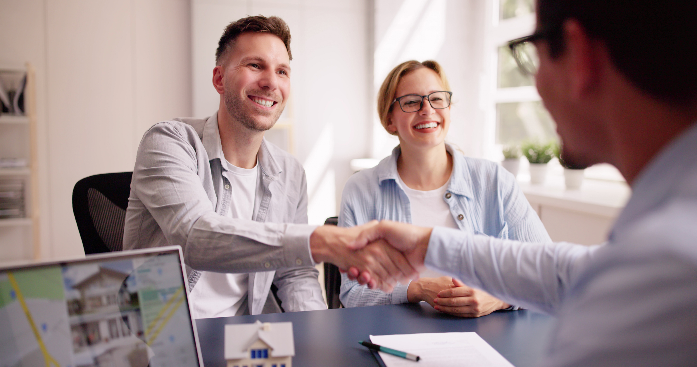 A California Pools designer shaking hands with homeowners at a consultation table