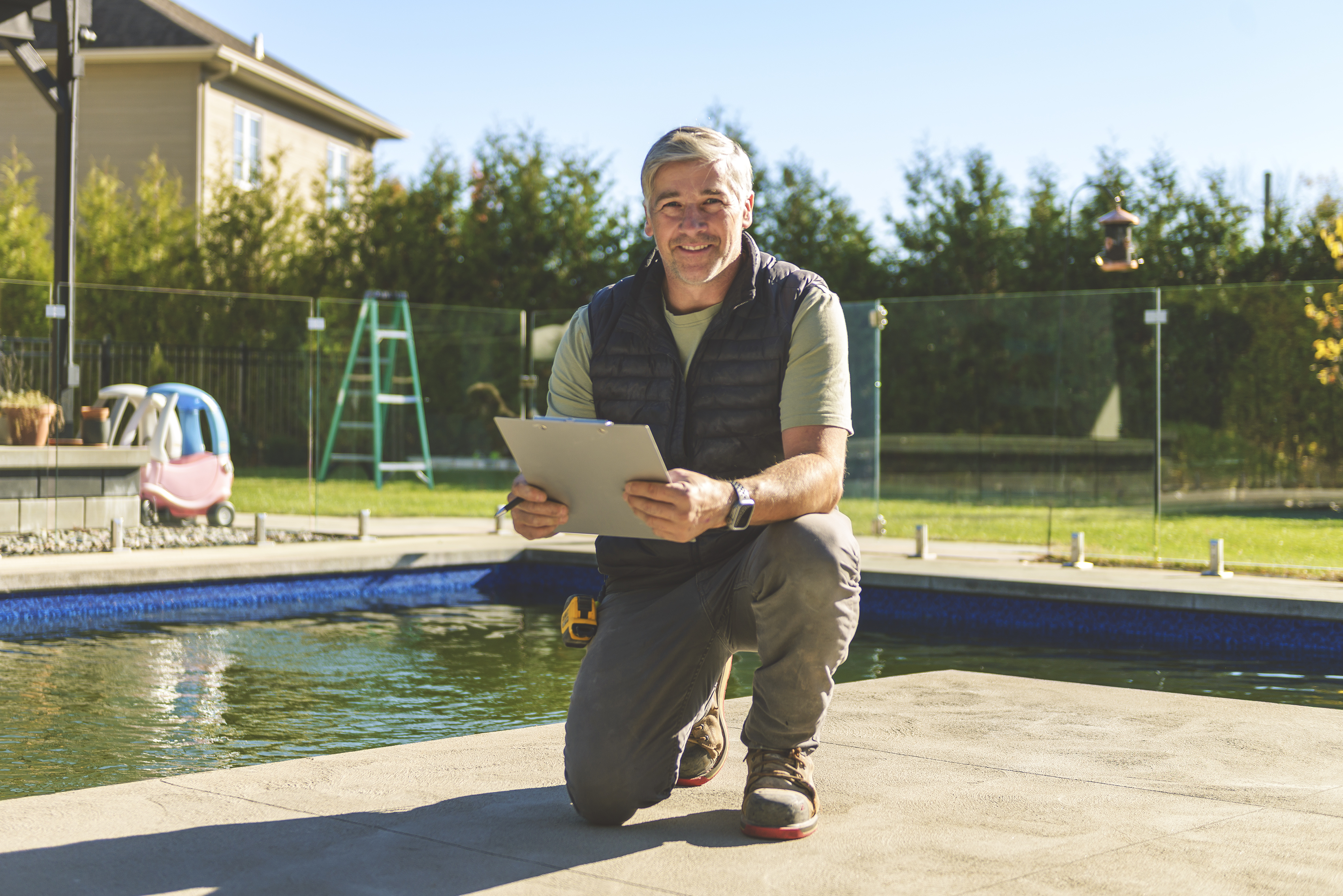 A California Pools project manager with a clipboard beside a finished pool