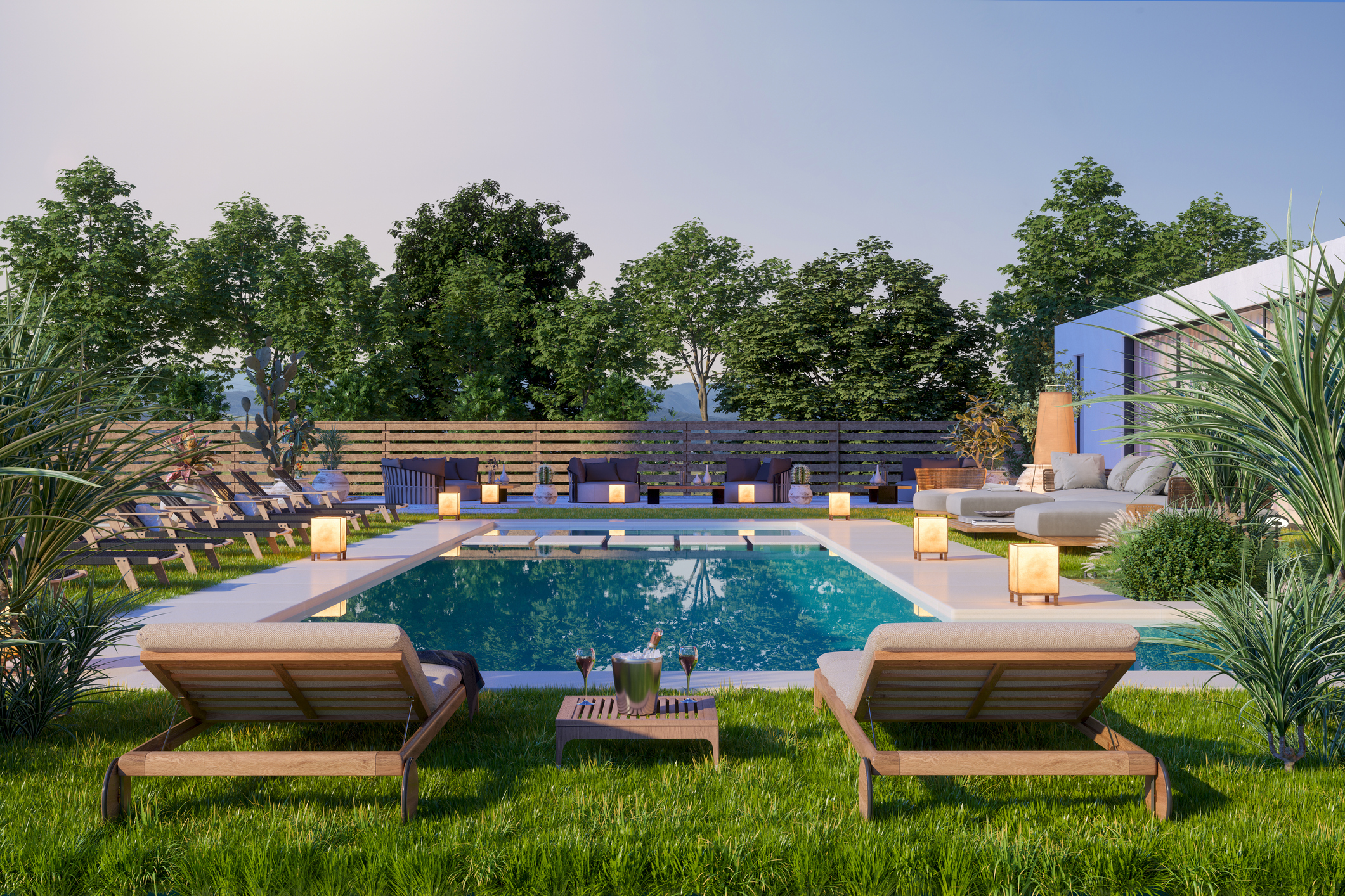 A completed backyard pool and spa glowing at sunset with lounge chairs on the lawn