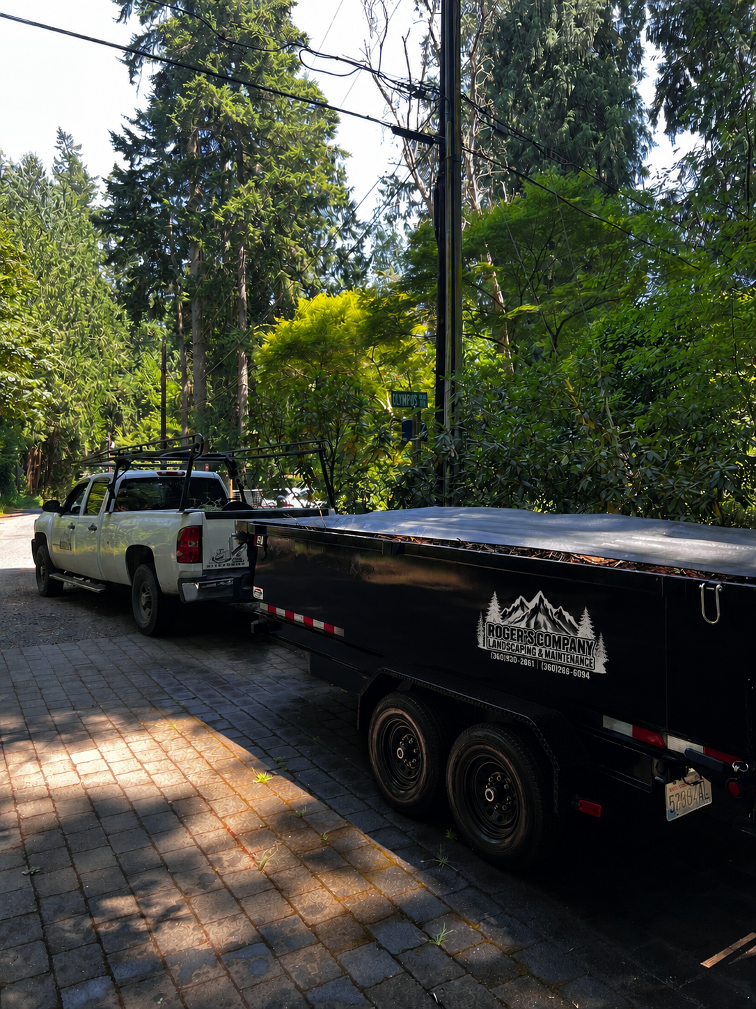 Roger's Company work truck and dump trailer loaded with yard debris on a driveway