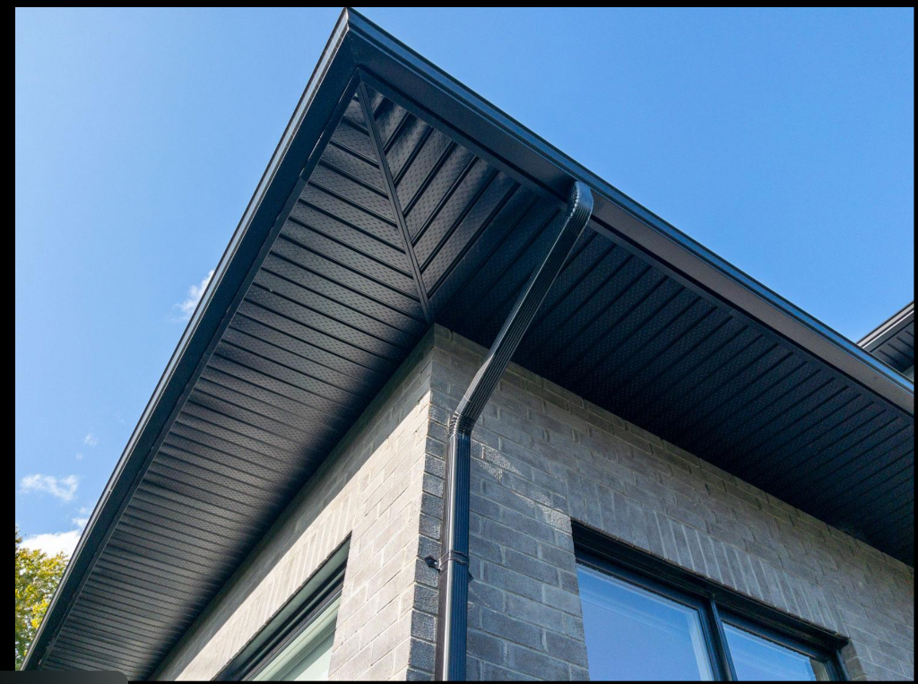 Black downspout and vented soffit detail on light grey brick home
