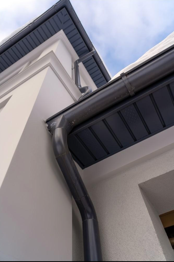 Charcoal aluminum gutter and downspout installation at building corner