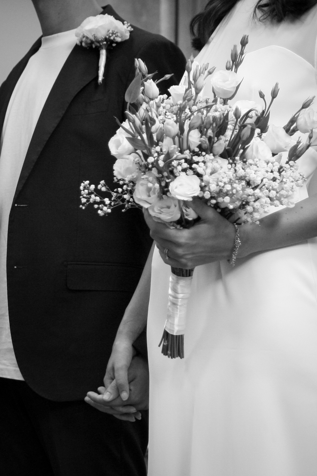 Primo piano delle mani intrecciate degli sposi con il bouquet