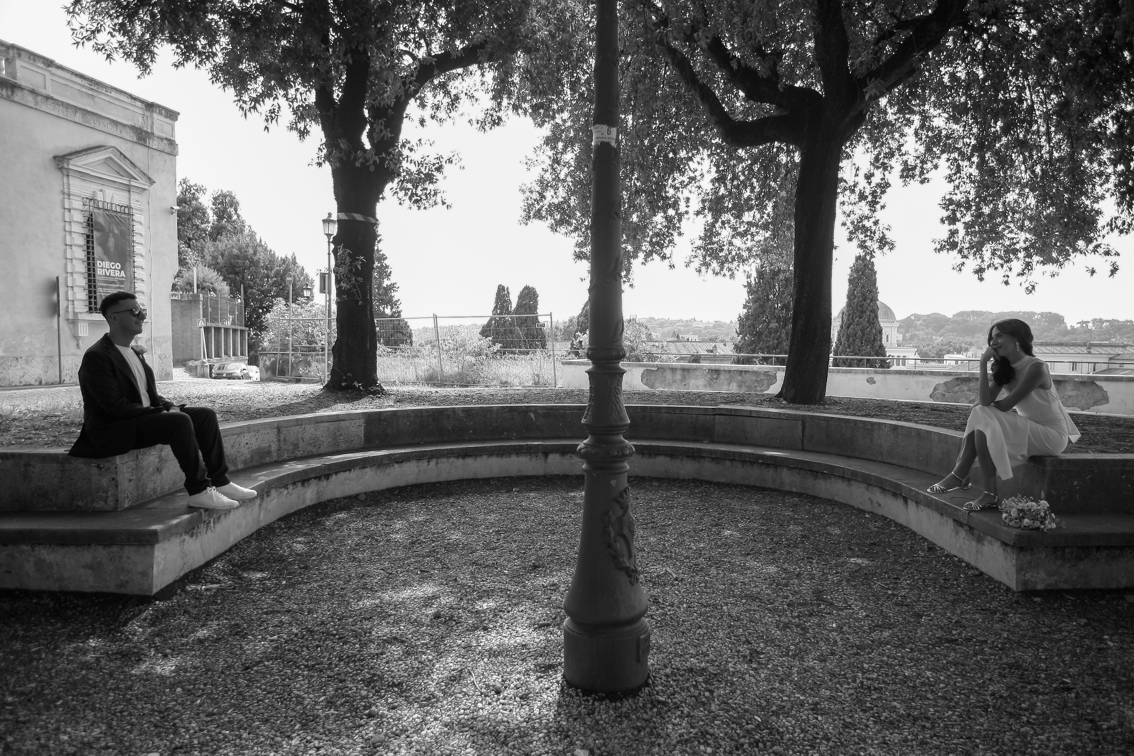Gli sposi seduti sulla panchina curva di pietra nel parco