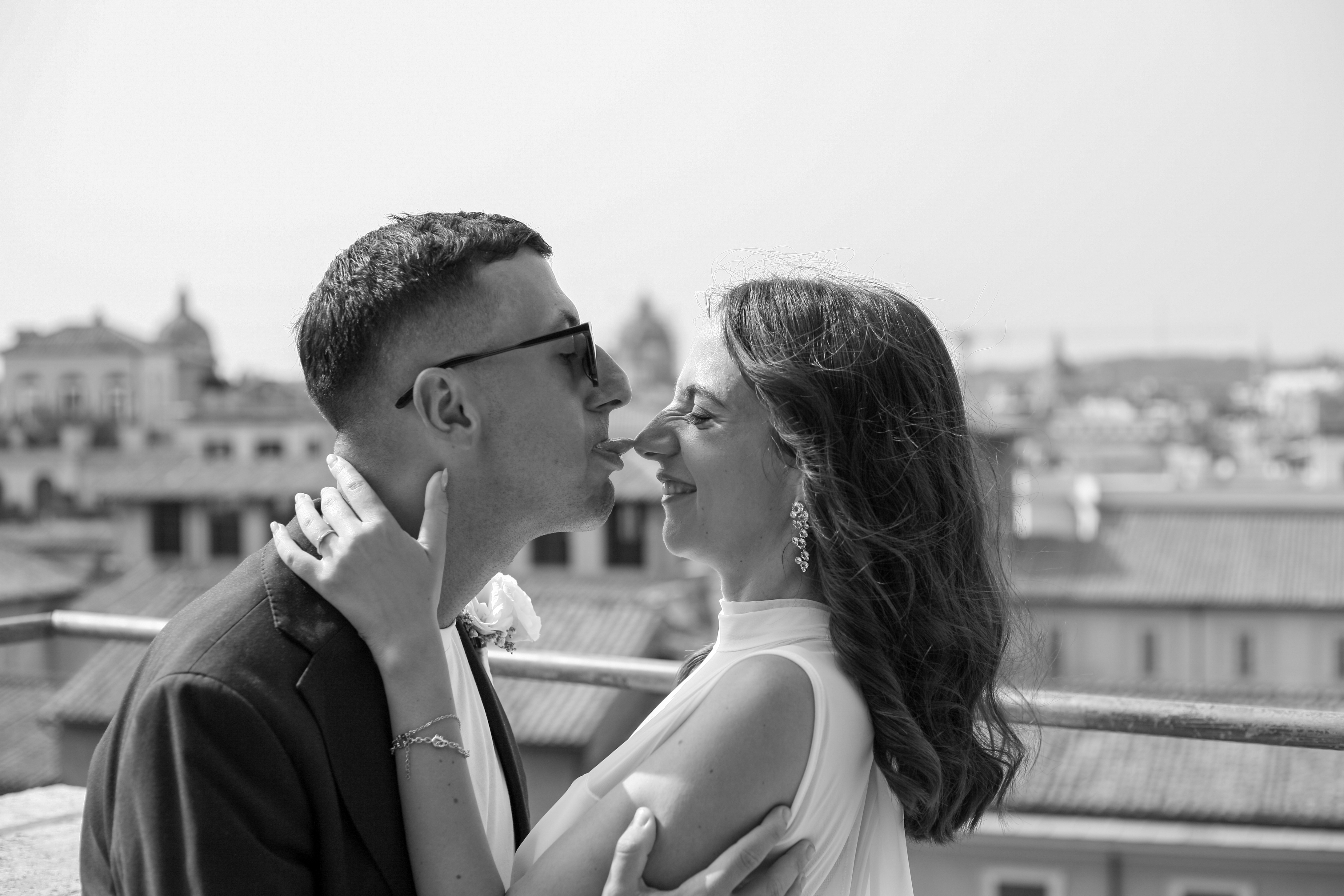 Lui fa la linguaccia sul naso di lei, momento giocoso sul terrazzo