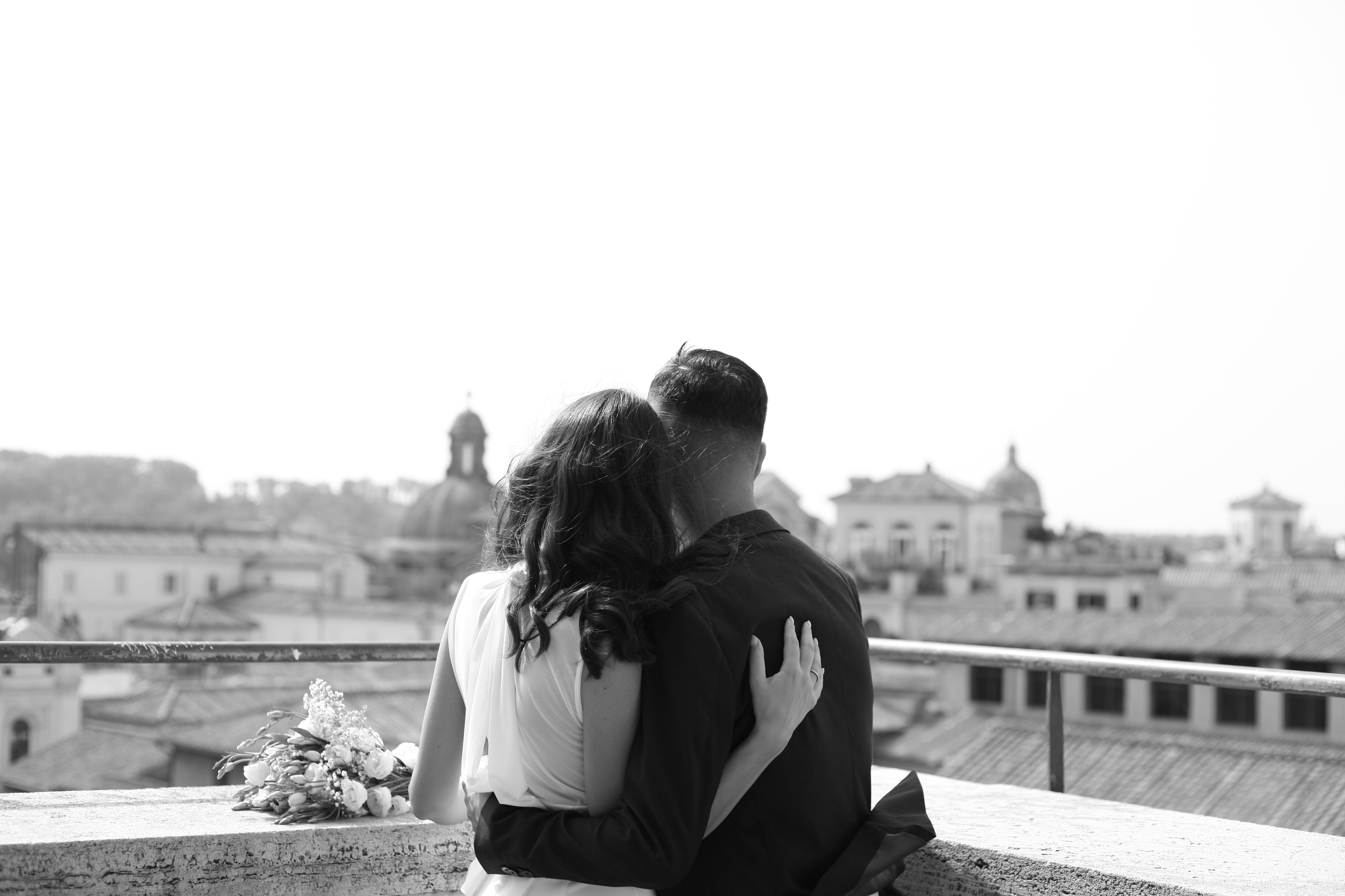 Gli sposi di spalle sulla terrazza, abbracciati davanti al panorama di Roma