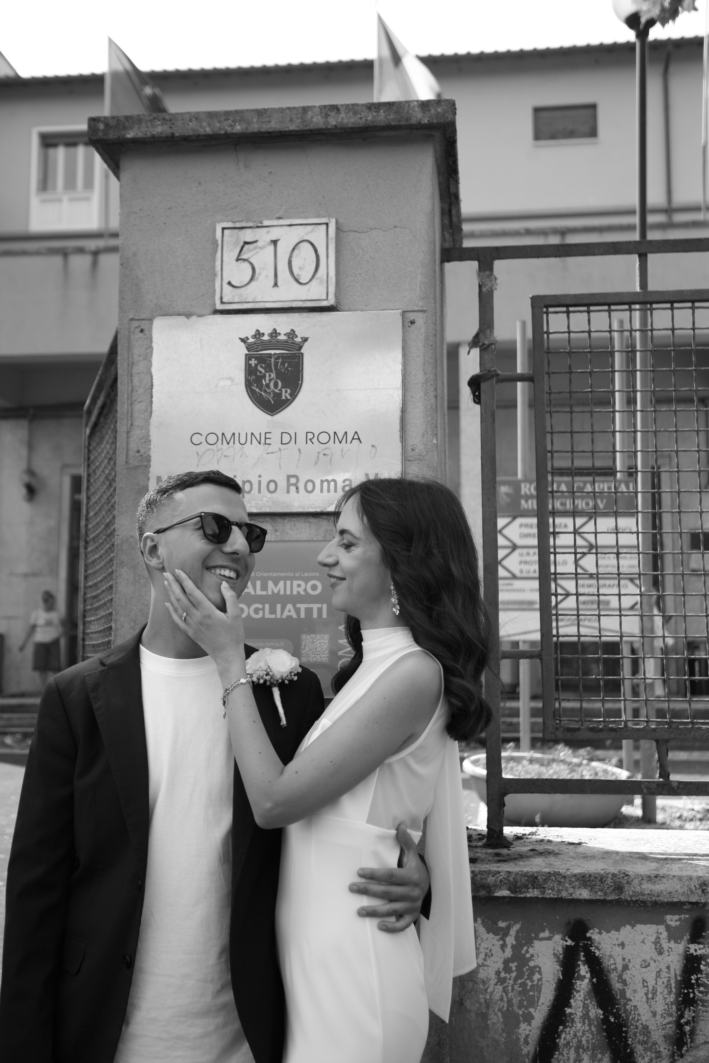 Carlotta ed Emanuele davanti al Municipio Roma V, lei gli sfiora il viso
