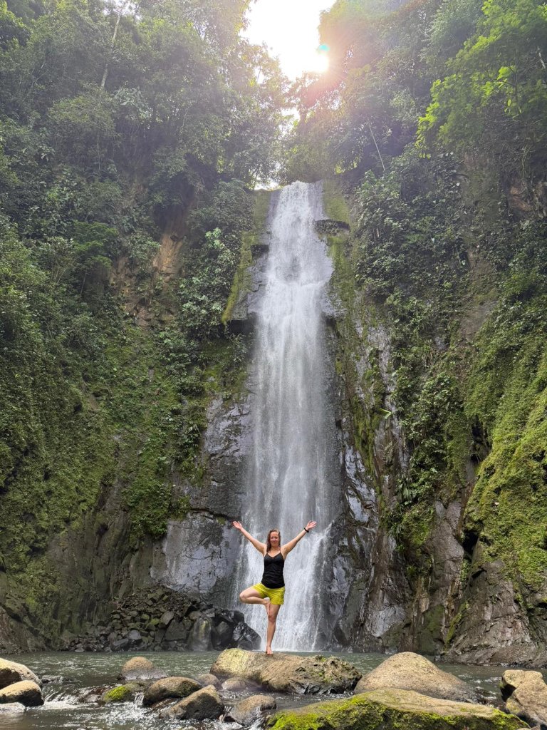 Coach in tree pose before a waterfall
