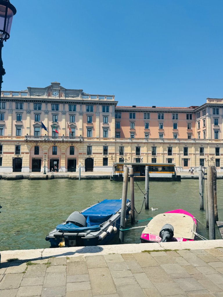 Historic building facade across a Venetian canal with docked boats