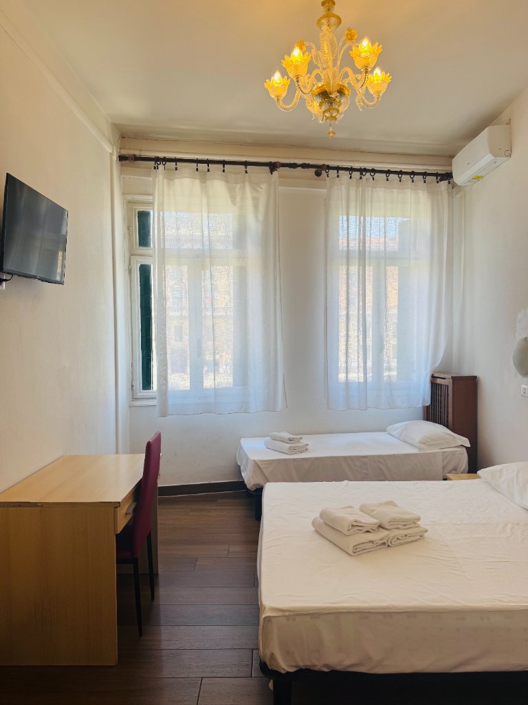 Hotel room with double and single beds, desk and chandelier