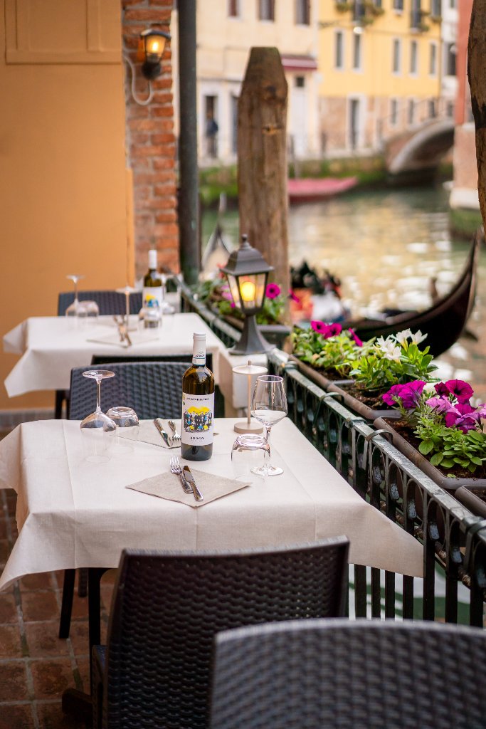 Outdoor terrace tables set along a Venice canal