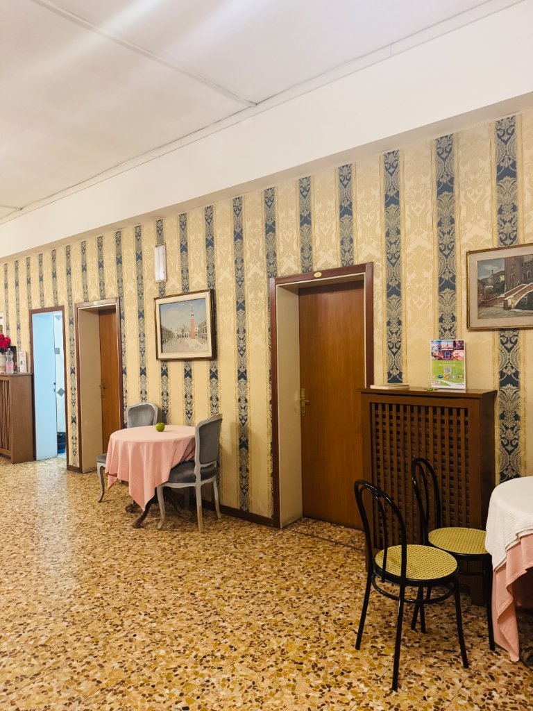 Hotel hallway with patterned wallpaper, bistro table and seating