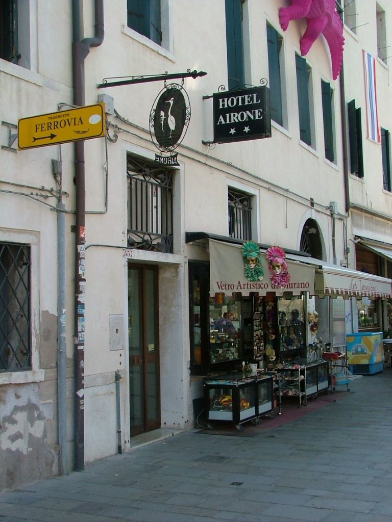 Exterior facade of Hotel Airone in Venice with hanging iron sign and canal walkway