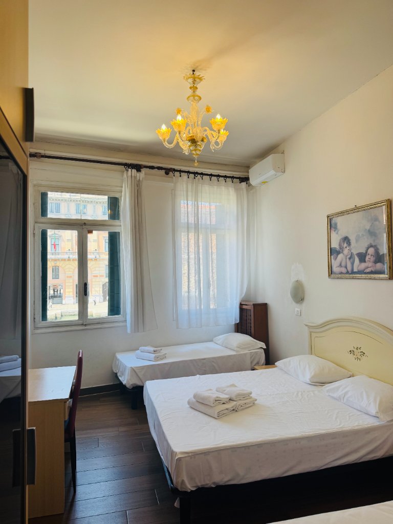 Hotel room with double and single beds, ornate chandelier and canal view