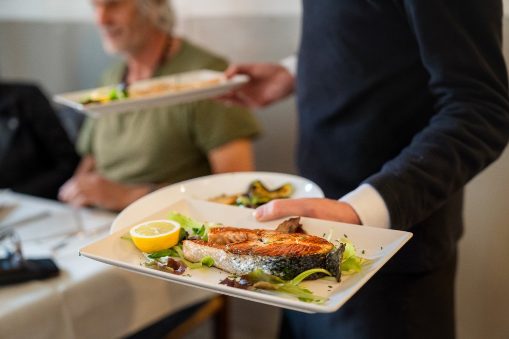 Waiter serving a grilled fish dish