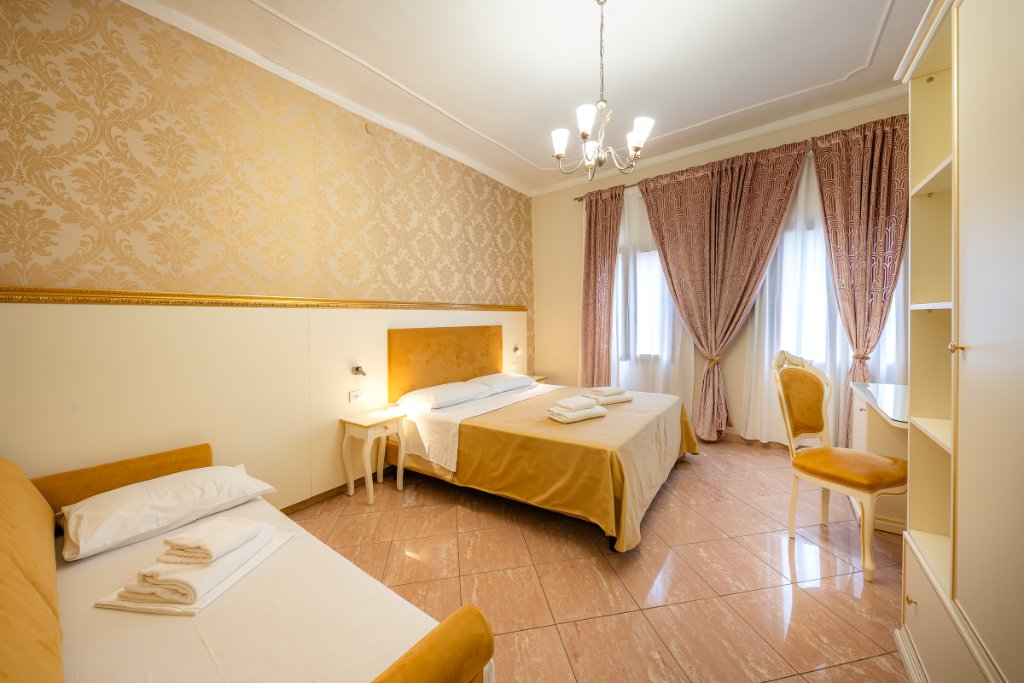 Superior Triple Room with golden bedspread, damask wallpaper and mauve curtains