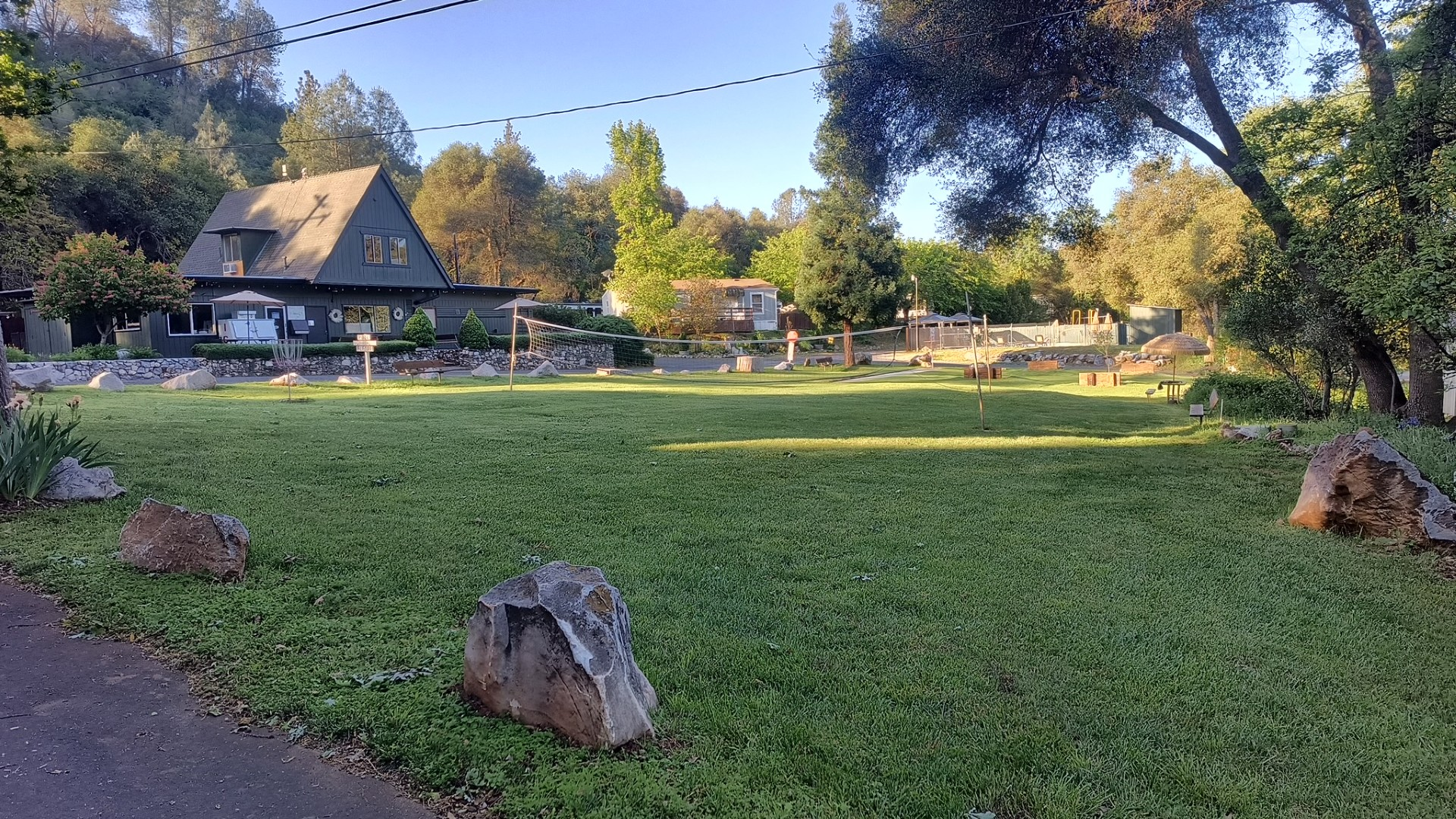 Expansive green lawn with a volleyball net and disc golf basket