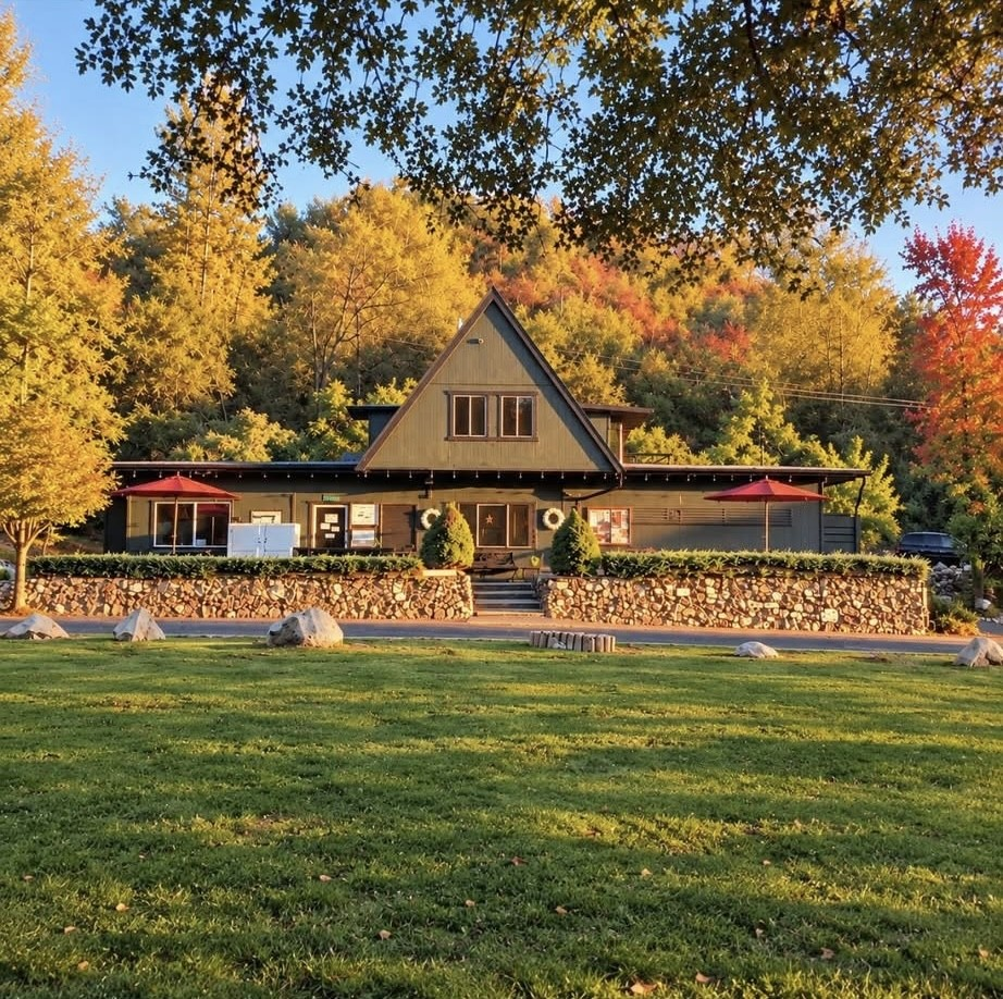 A-frame lodge with red patio umbrellas and a stone retaining wall on the lawn