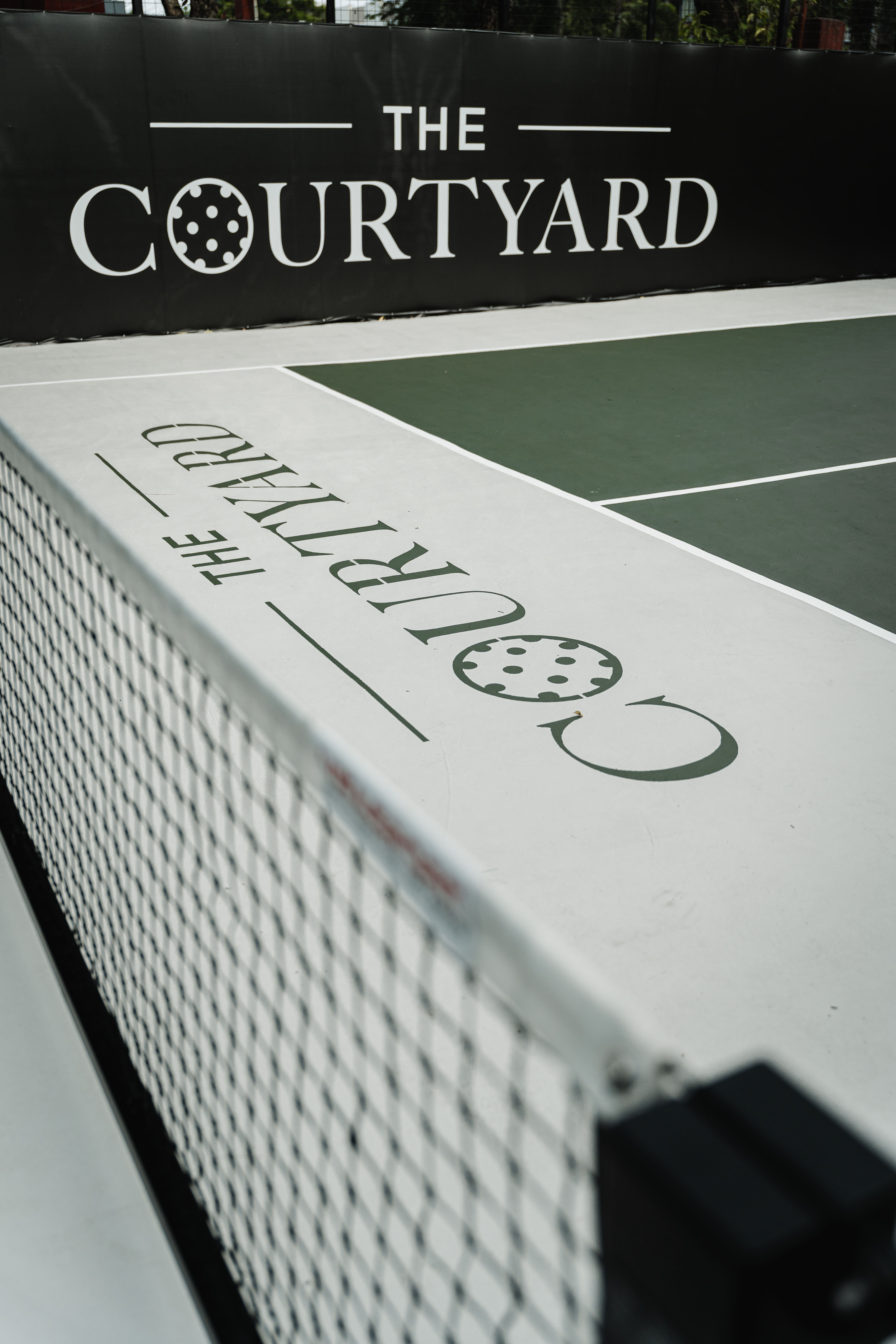 Close-up along the net line showing the Courtyard court branding