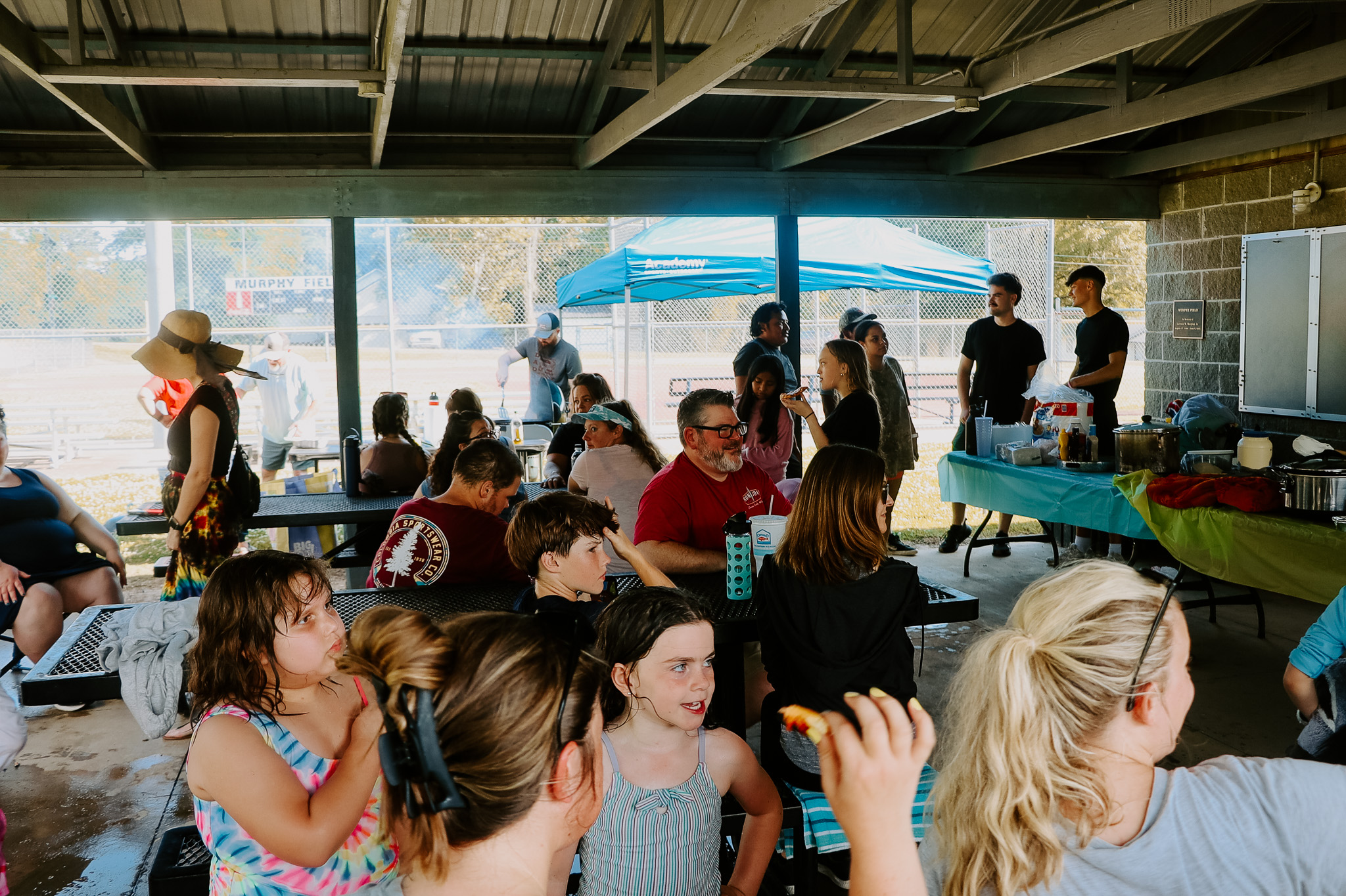 Community gathering under a park pavilion during a House Group event