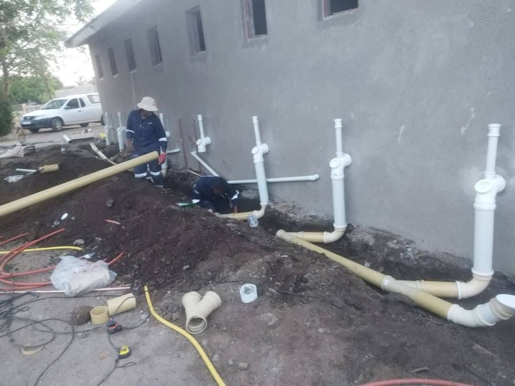 Team installing PVC drainage pipes on site