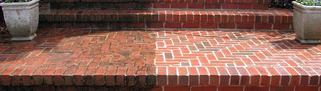 Before and after pressure washing on a brick porch — grime and moss blasted away to reveal clean, vibrant brick