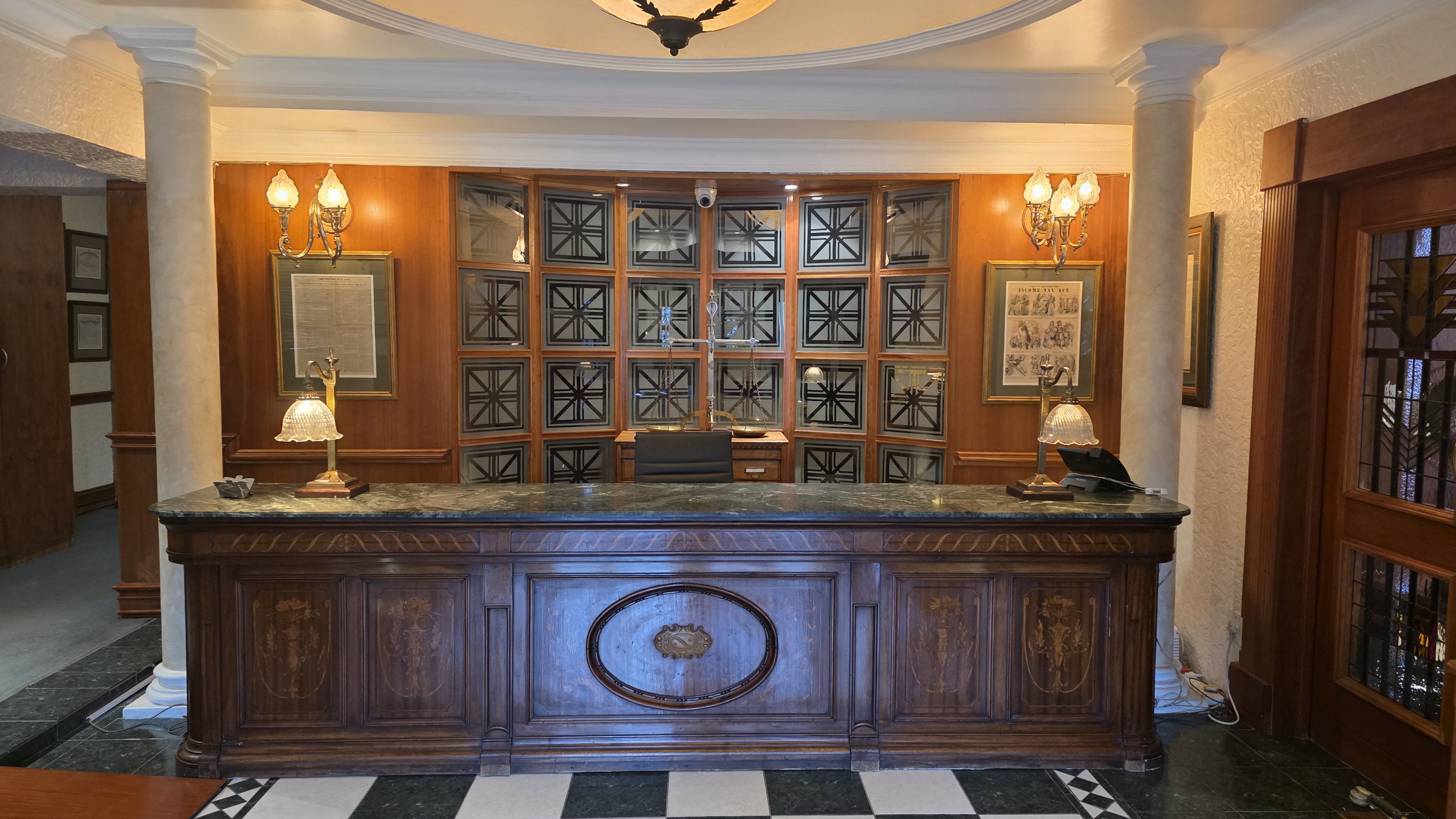 Traditional wood-panelled reception with a green marble desk and brass scales of justice