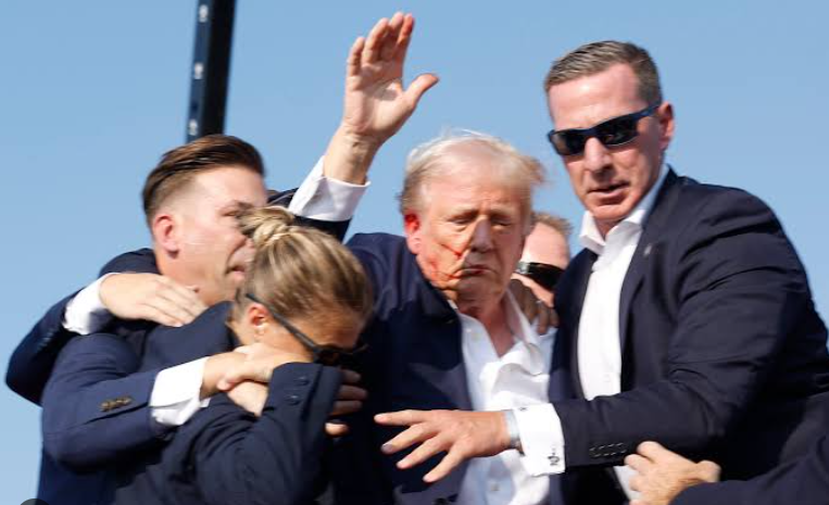 Donald Trump surrounded by Secret Service agents being walked off stage blood on face fist raised Butler Pennsylvania