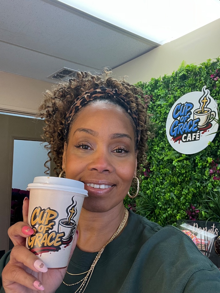 A woman holding a Cup of Grace coffee