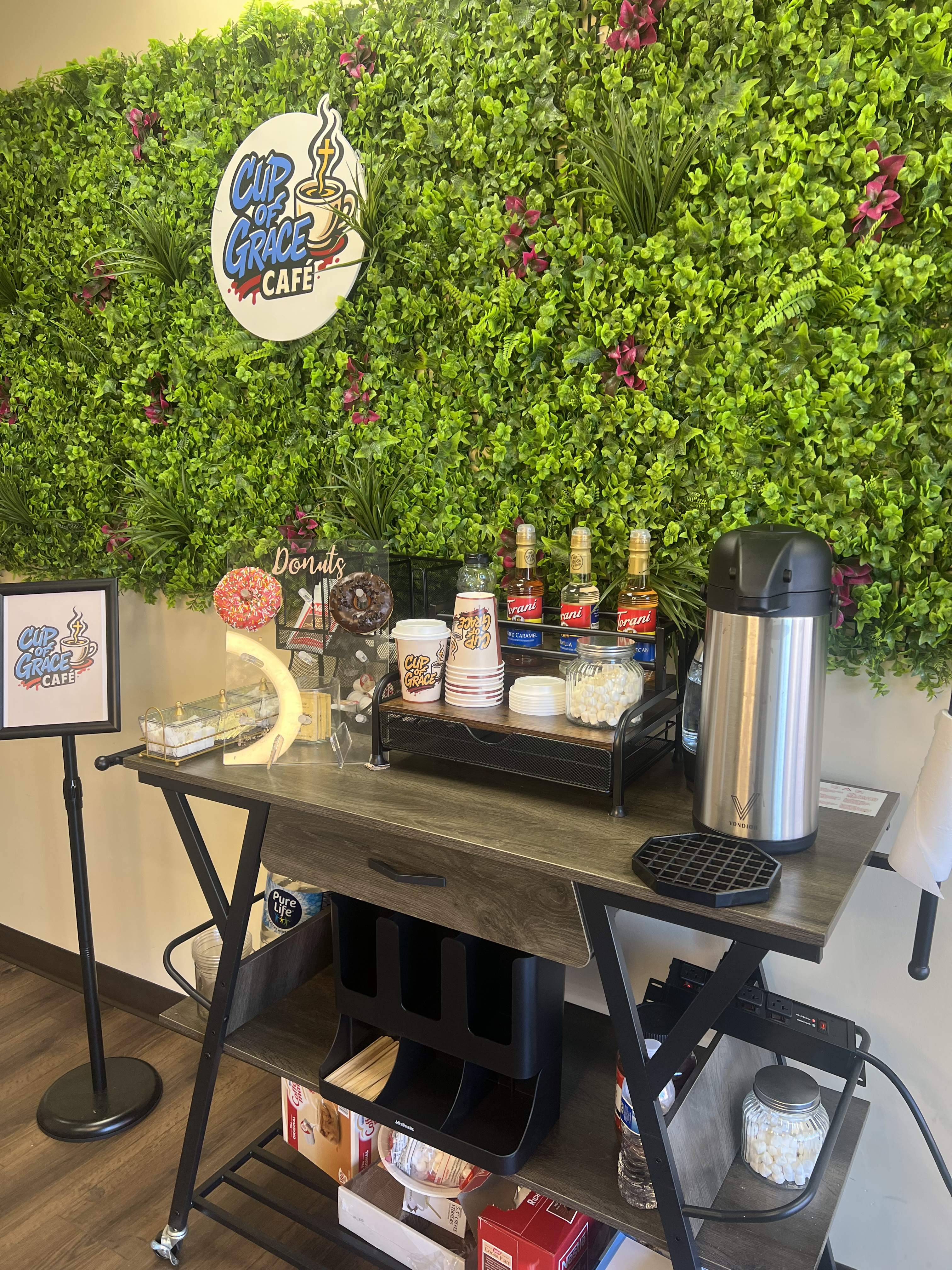 The Cup of Grace Café coffee cart with syrups, donuts, and supplies