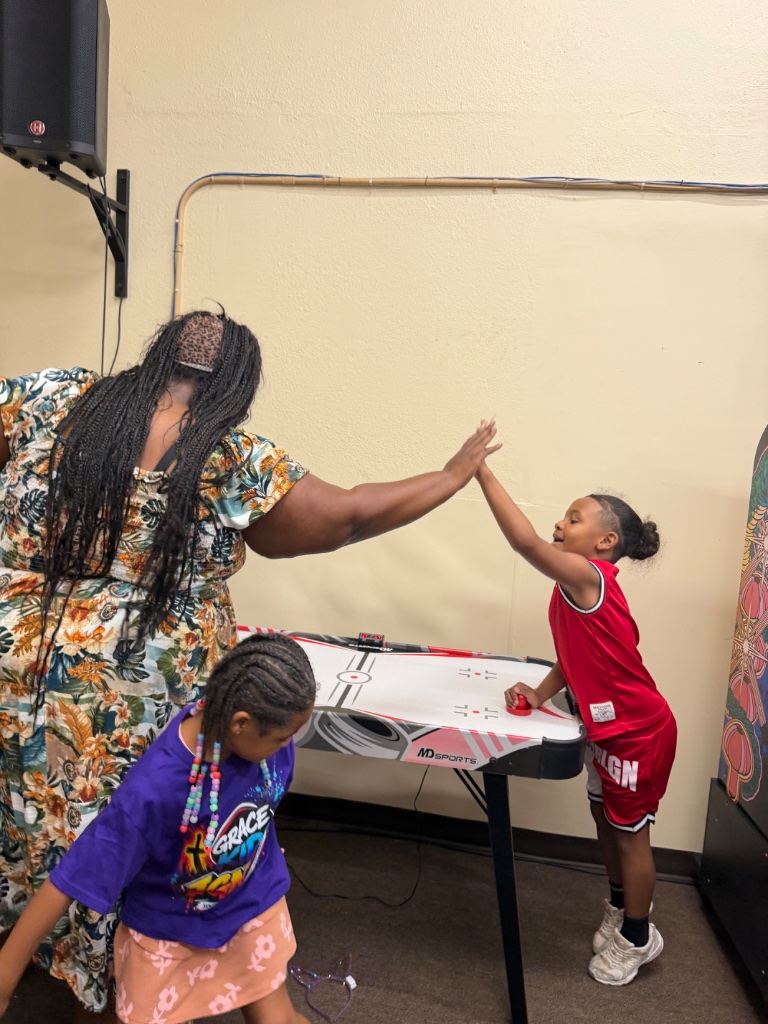 Leader and child high-fiving over air hockey table