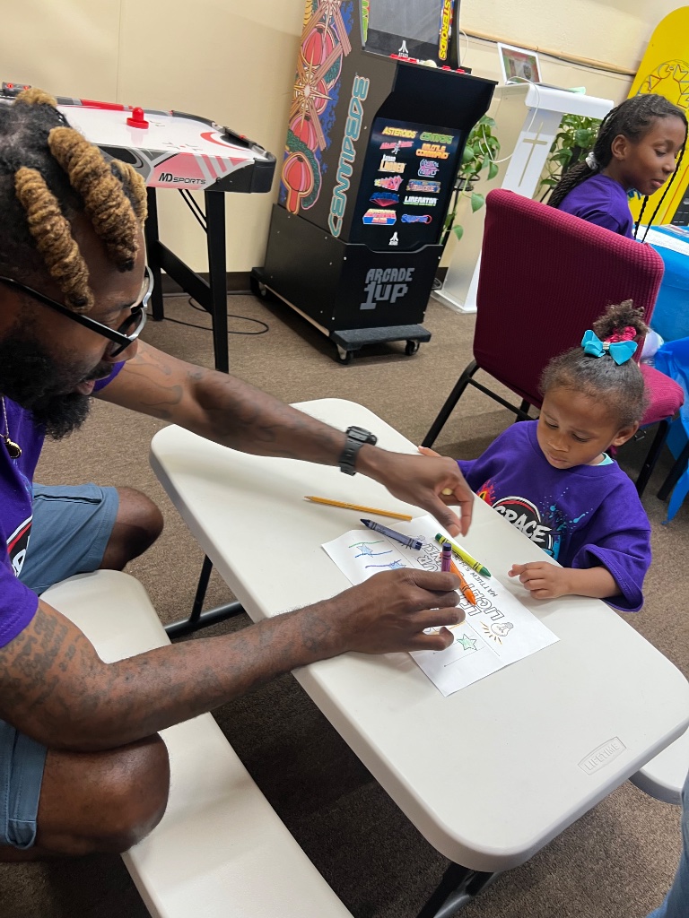 Leader helping child color at activity table