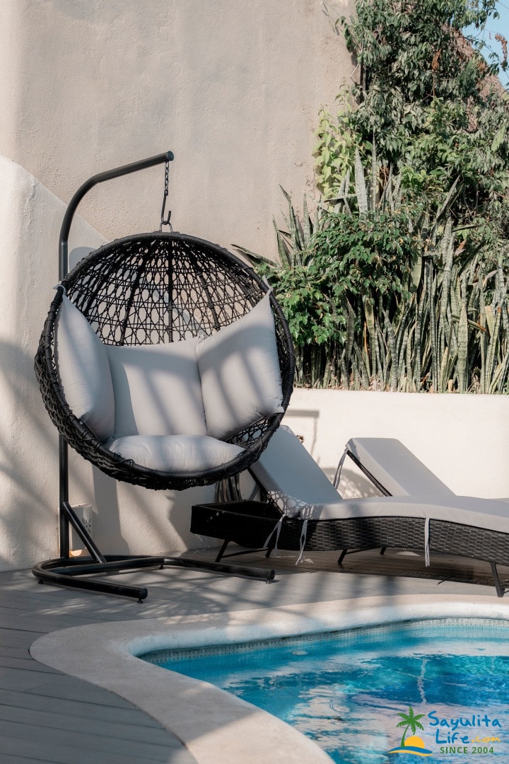 Hanging egg chair and sunbeds by the pool