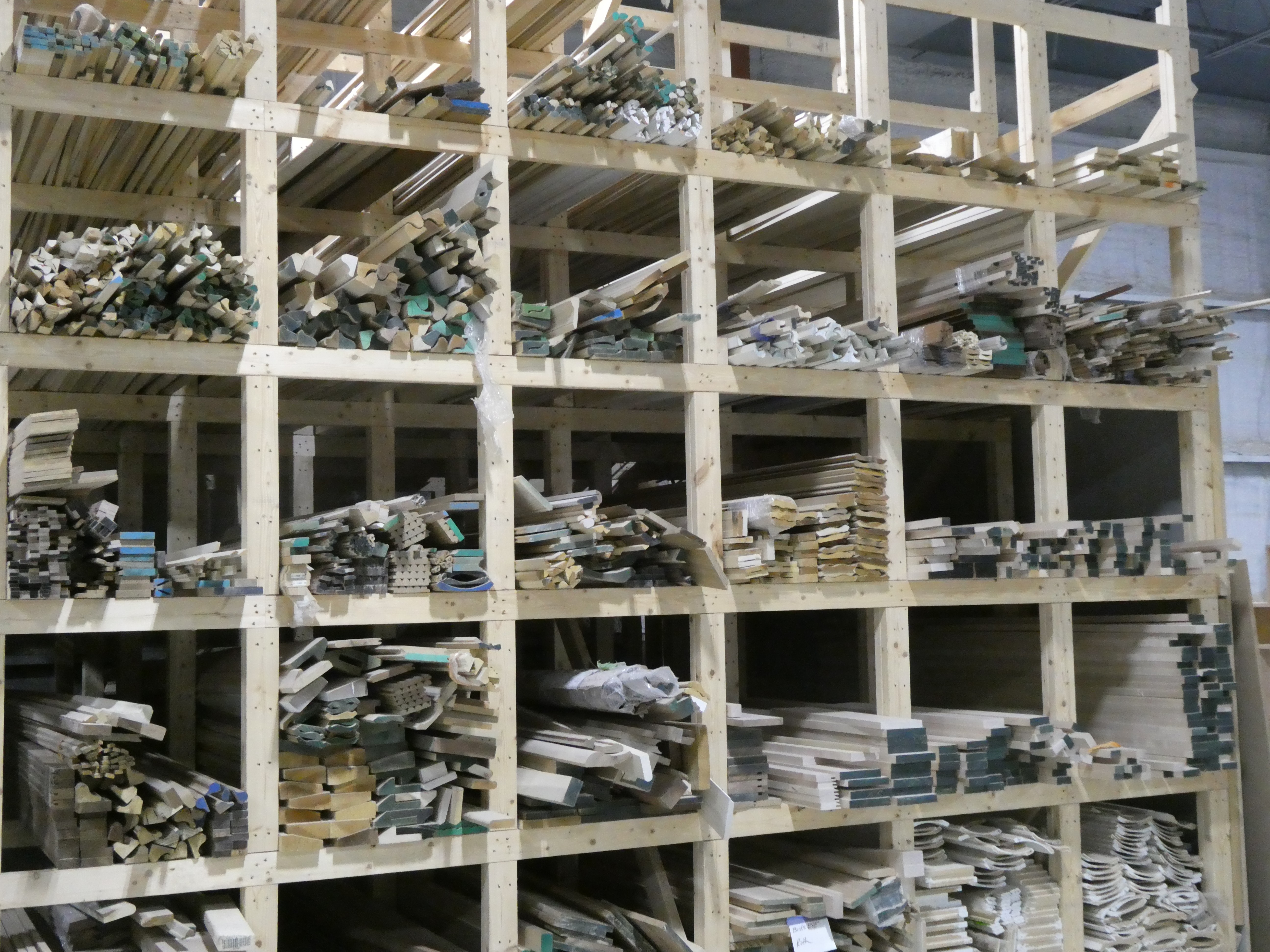 Shop racks filled with milled moulding stock sorted by profile.