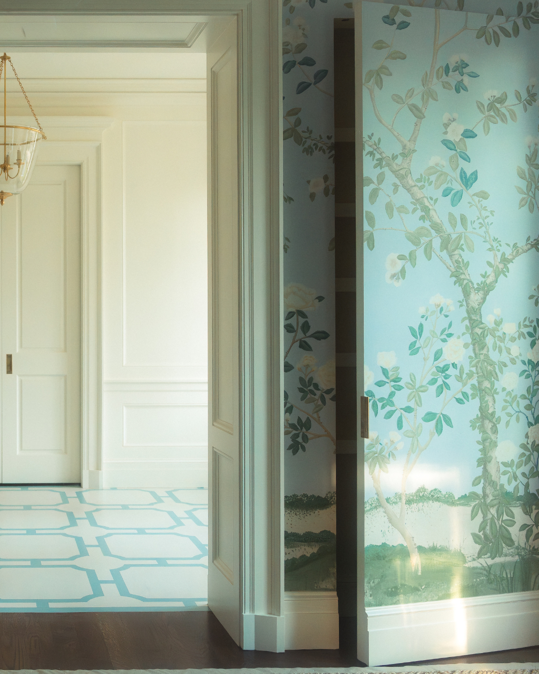 A partially open secret door covered in floral wallpaper sits beside white paneled walls and door casings.