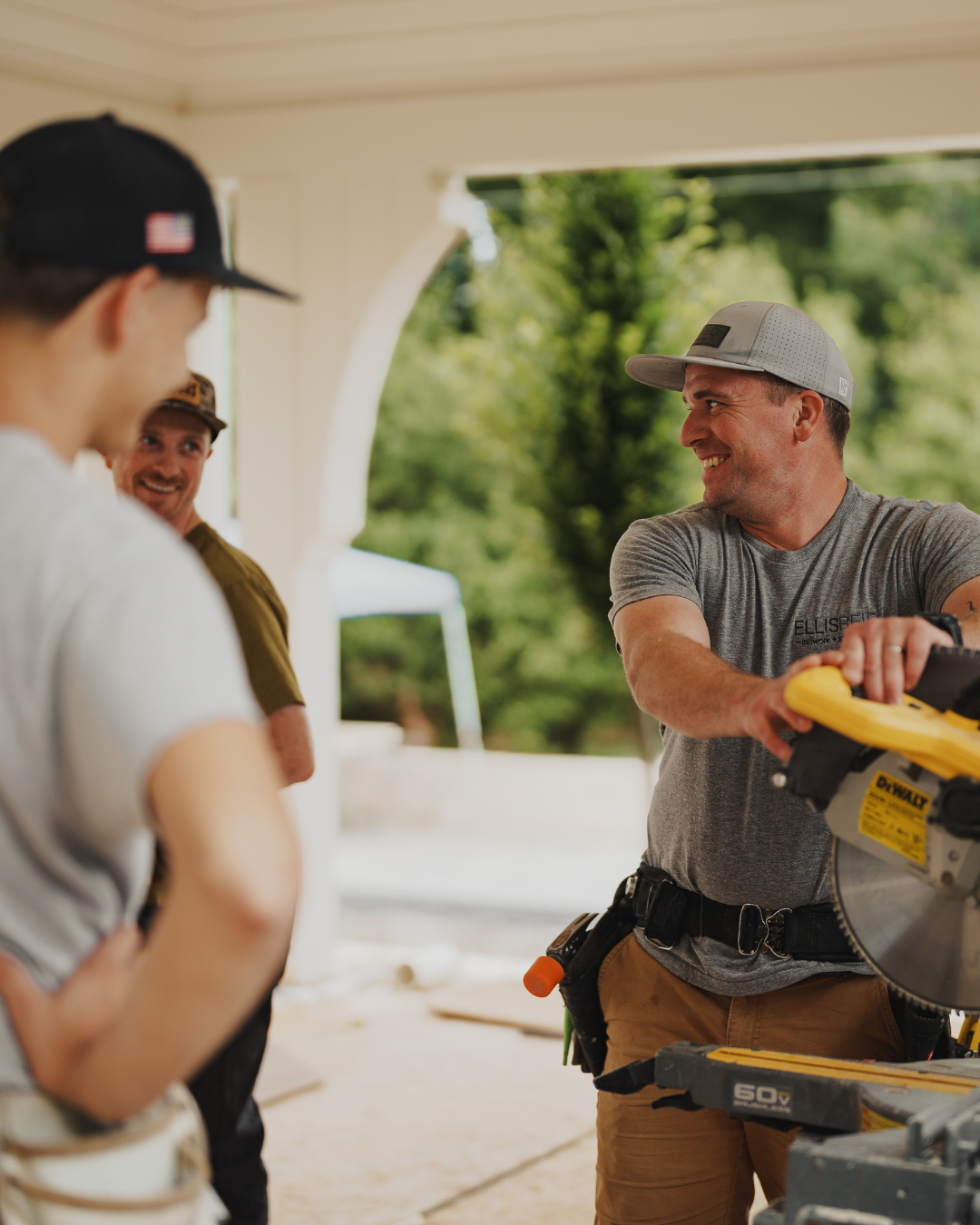 Team of carpenters working on a covered exterior porch featuring arched architectural openings.