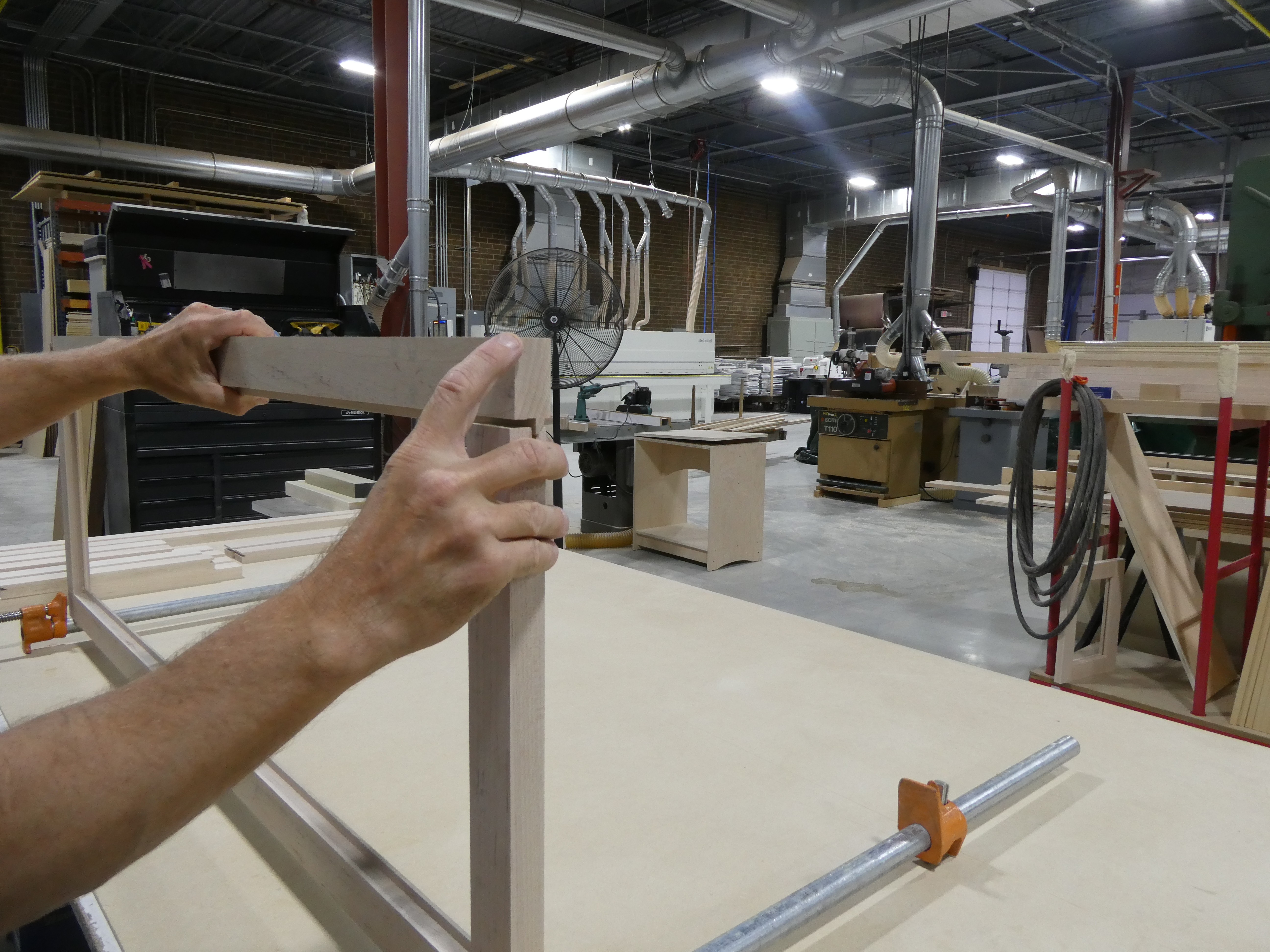 Wide view of the Ellis-Reid shop floor, with frame assemblies clamped up on the bench and machinery beyond.
