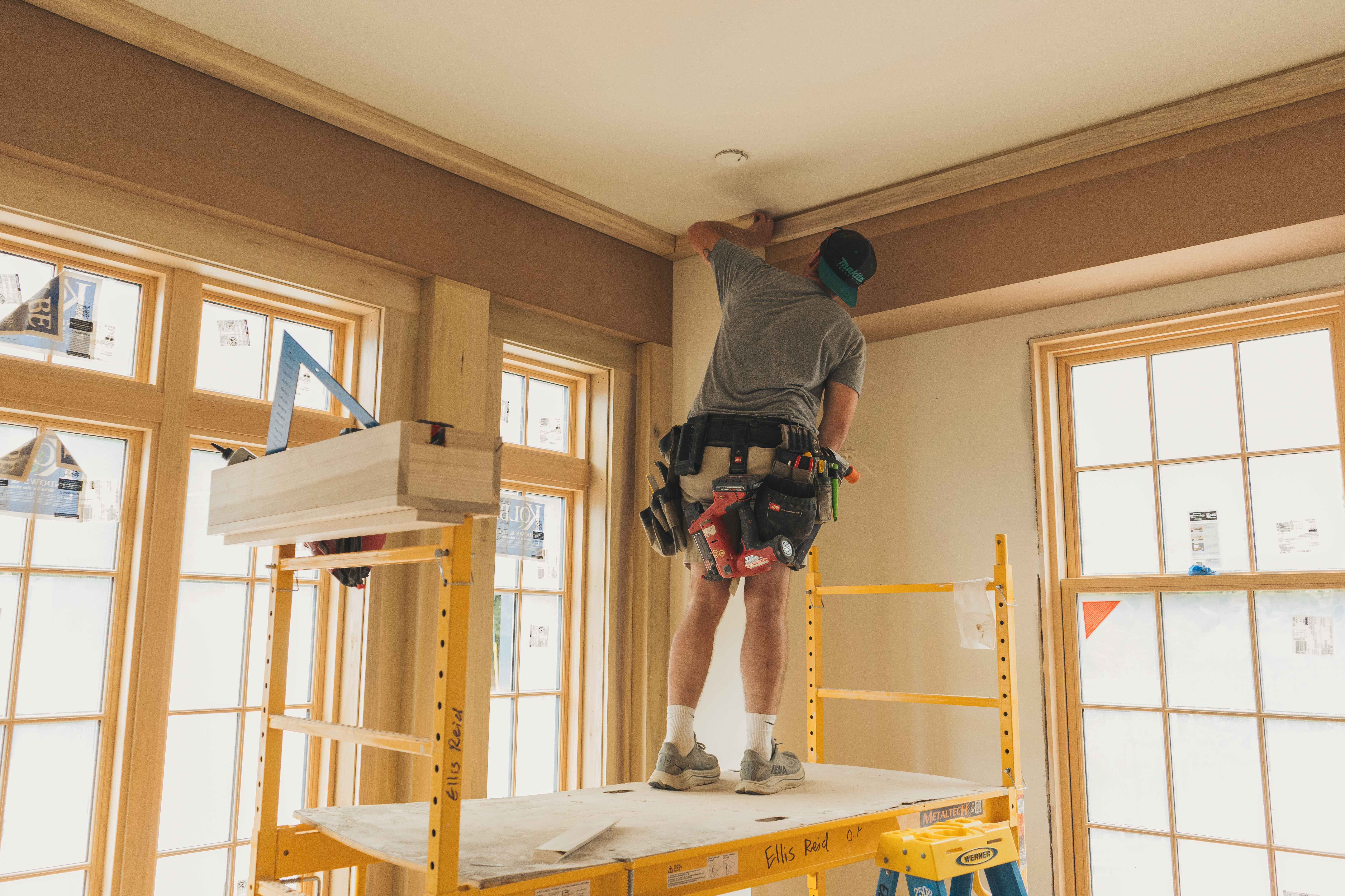 Ellis-Reid carpenter on a rolling scaffold setting crown moulding