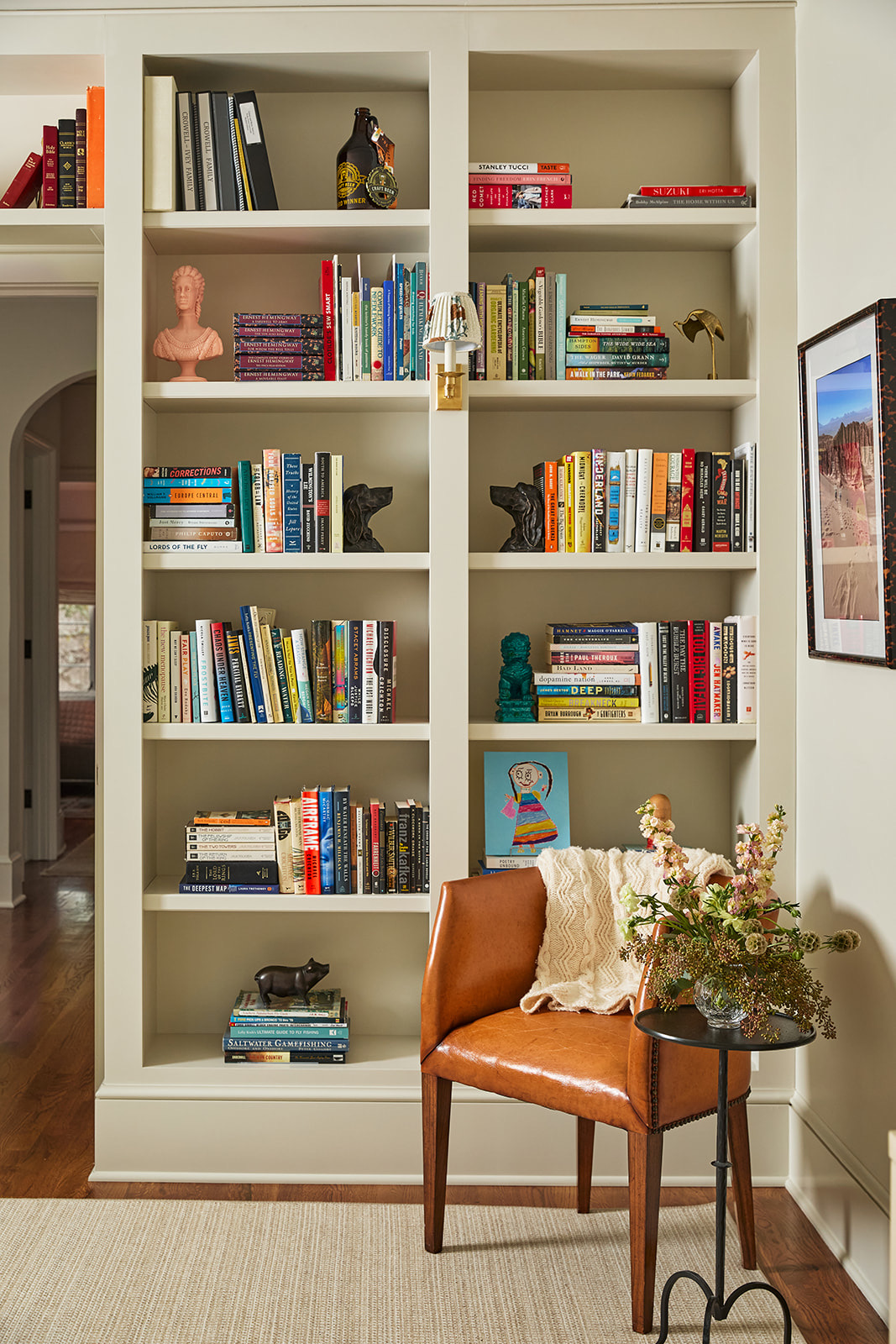 Floor-to-ceiling built-in white bookshelves with adjustable shelves and a baseboard in a study.
